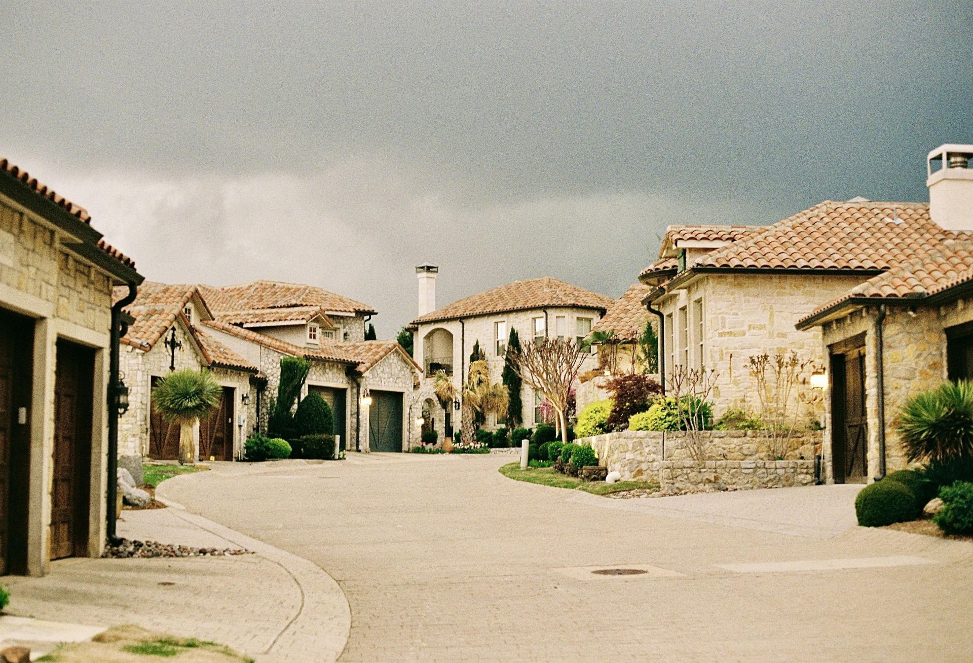 Picturesque stone cottages in a residential area under an overcast sky.